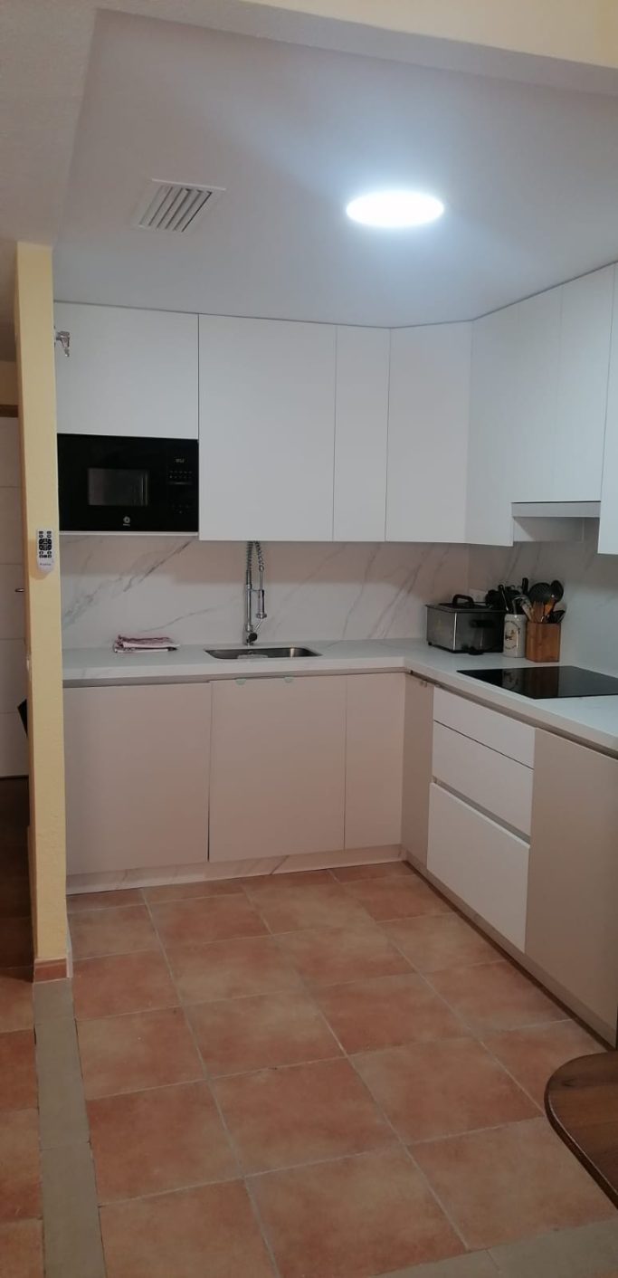 Cocina blanca en L con muebles a medida